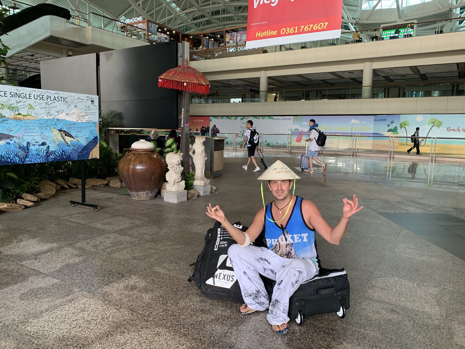 Nikita at Bali airport wearing a conical hat, playful pose