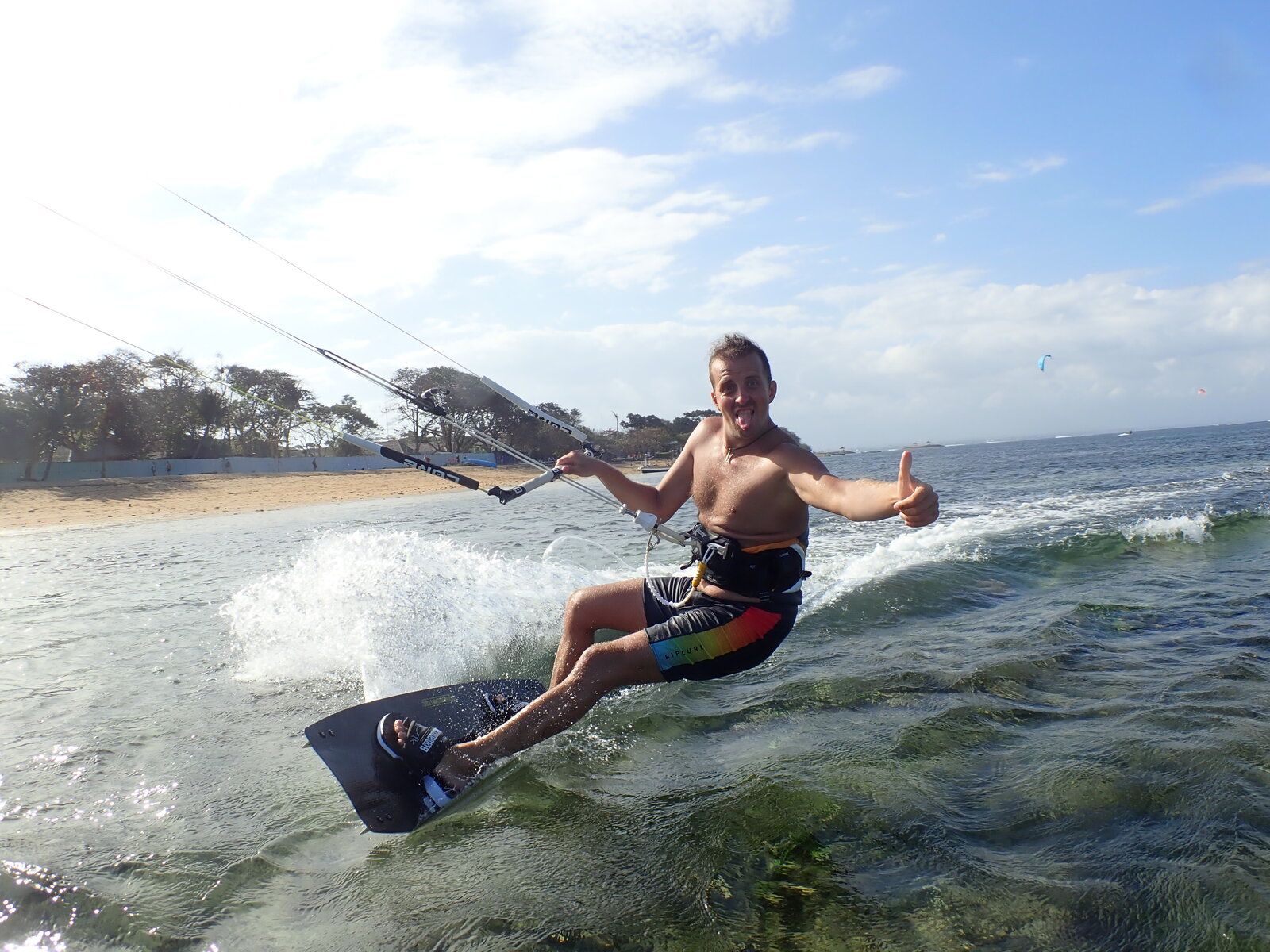 Nikita kiteboarding in Bali, giving thumbs up while riding