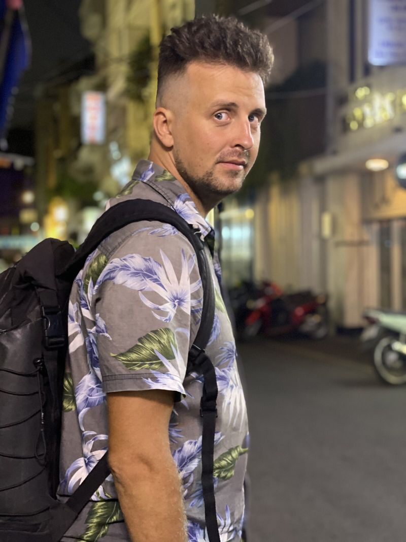 Nikita on a night street in Da Nang, Vietnam, wearing a backpack